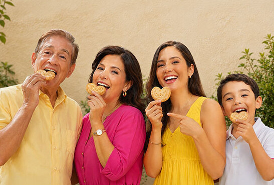 Una familia de tres generaciones ríe mientras comparte orejitas.